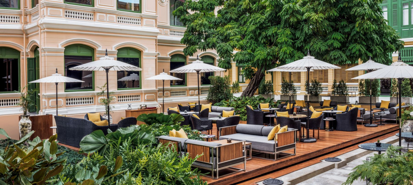 The garden terrace at The House on Sathorn, set against the 1889 Neoclassical mansion’s ochre facade and green shuttered windows