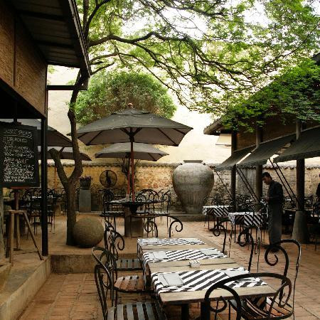 One of the three courtyards at Paradise Road The Gallery Café, with the original compound walls and mature trees that predate the restaurant's 1998 opening