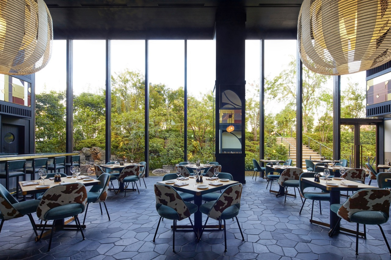 The main dining room of Kosa at Ace Hotel Kyoto, with full-height glazing overlooking the courtyard garden