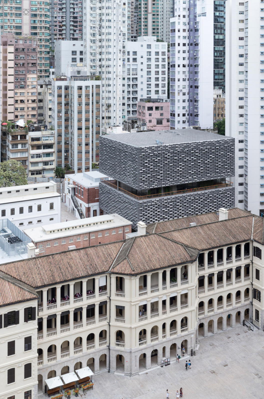 The Parade Ground of Tai Kwun, with the restored collonaded buildings of the former Central Police Station compound in the foreground and one of Herzog & de Meuron’s two new cast aluminium-clad insertions rising behind