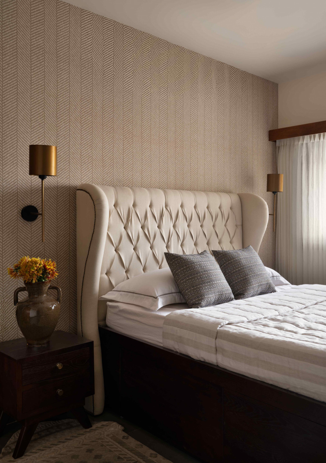 A Chesterfield wingback bed against a Chevron-patterned wallpaper