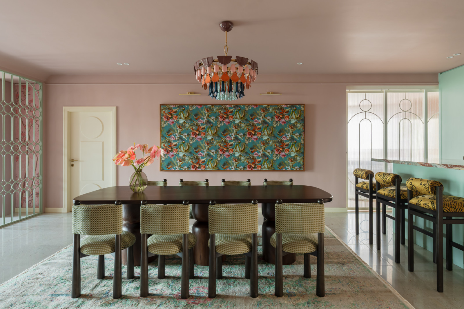 The dining room viewed from the opposite angle, with the mint-green geometric metal screen partition visible beyond, separating the dining and living area