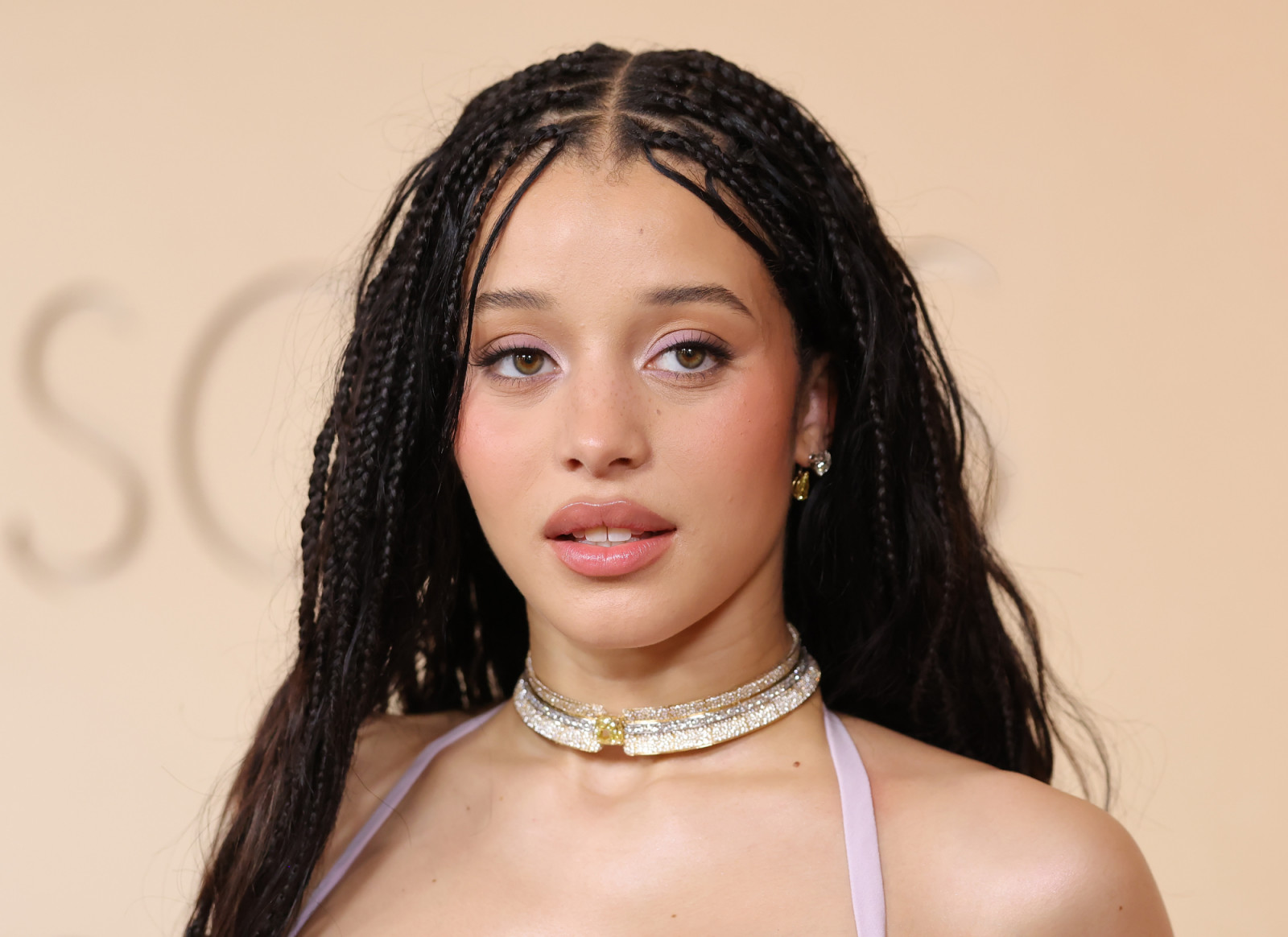 Chase Infiniti debuted on the Oscars red carpet in a layered lavender Louis Vuitton gown, paired with a De Beers choker and textured braids for a modern, sculptural finish (Photo: Mike Coppola/Getty Images)