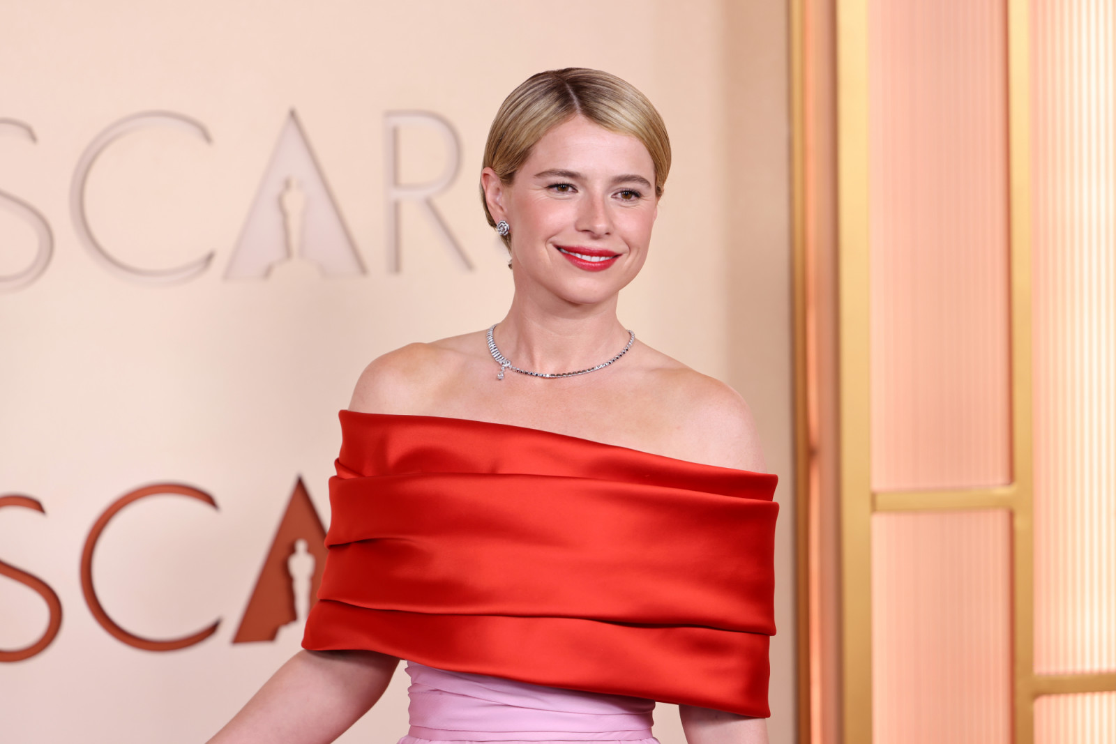 Jessie Buckley wore a pink-and-red Chanel gown with a structured silhouette, complementing her minimal makeup and sleek hairstyle (Photo: Julian Hamilton/Getty Images)
