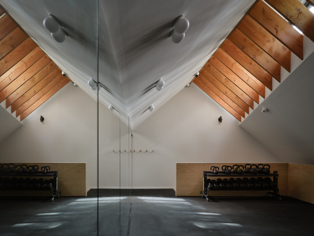 The upper-level gym is located within the angled volume that also houses the garage