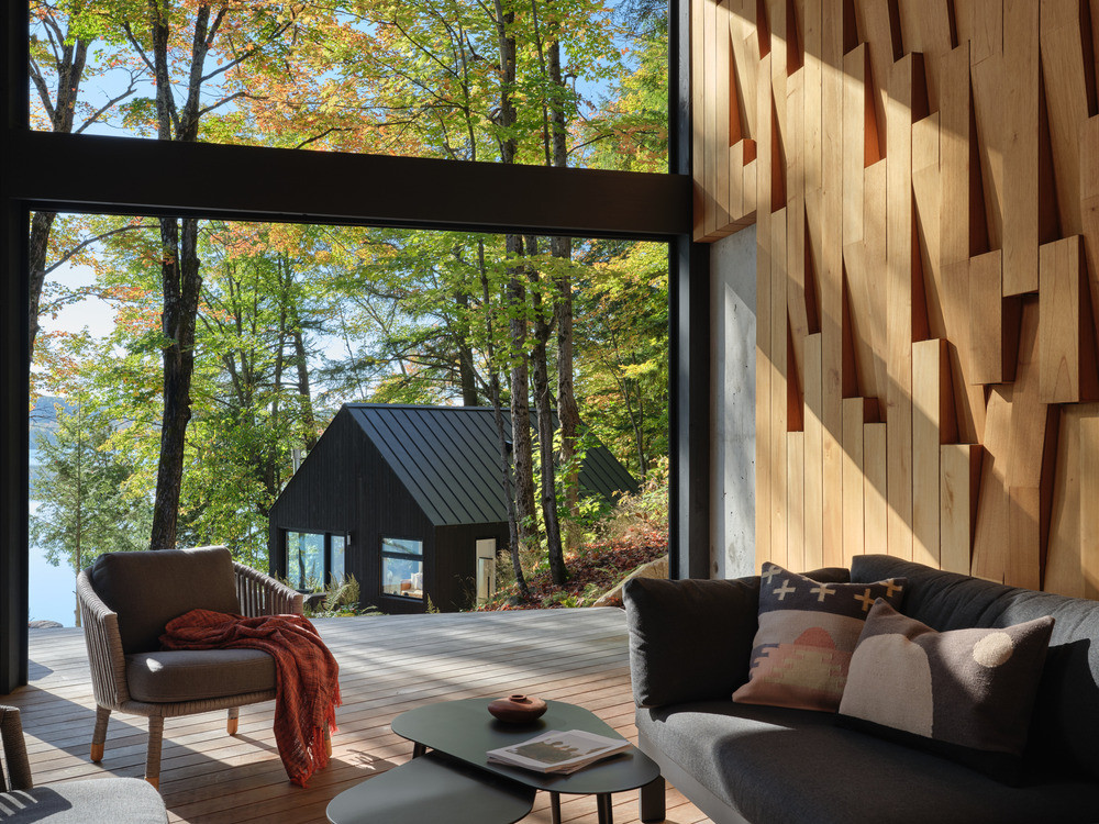 The Muskoka Room in daylight, with Victoria Fard’s cedar feature wall in relief and the reclad bunkie visible through the floor-to-ceiling glazing beyond