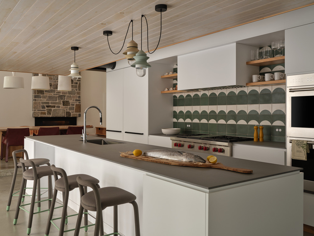 The kitchen on the lower ground level, with hand-painted cement tile splashback, open timber shelving, and a large island