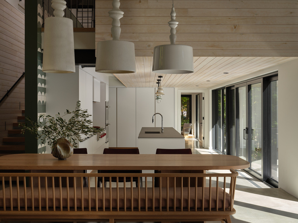 The dining area on the lower ground level, looking towards the kitchen and the glazed doors opening onto the terrace