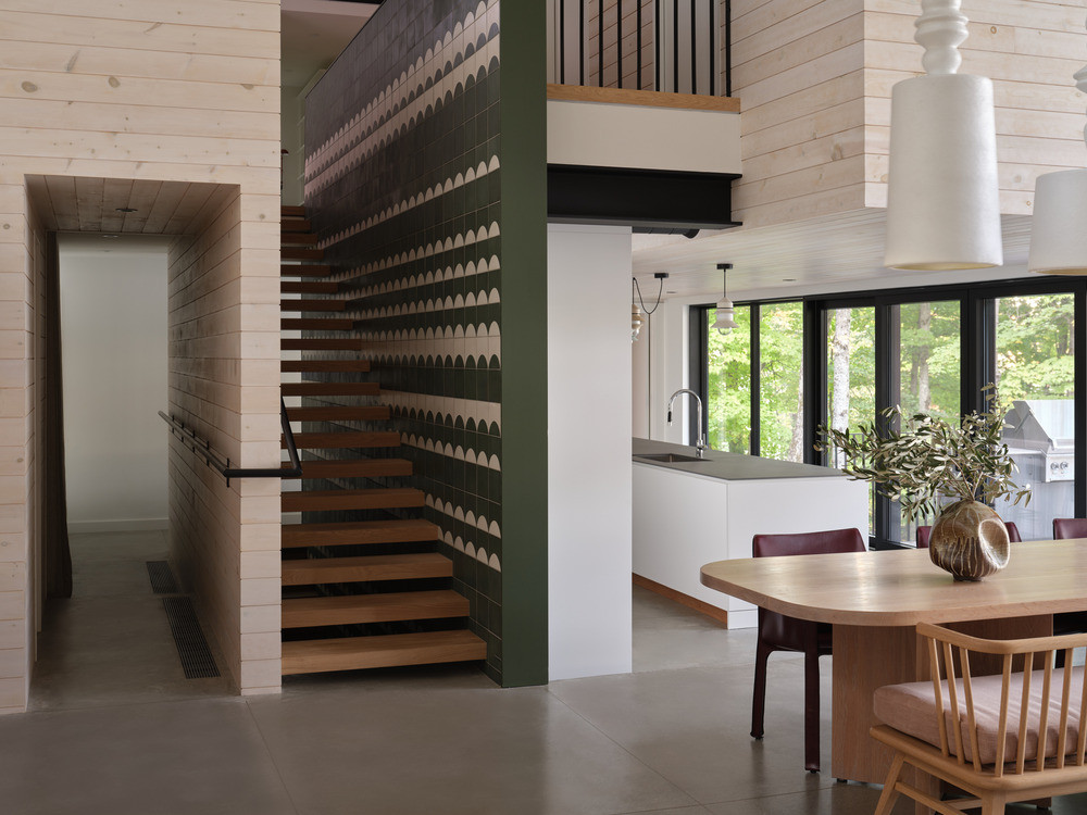 The open-plan lower level, with the main stair — its risers set against hand-painted cement tile — connects the social spaces to the upper-level bedrooms