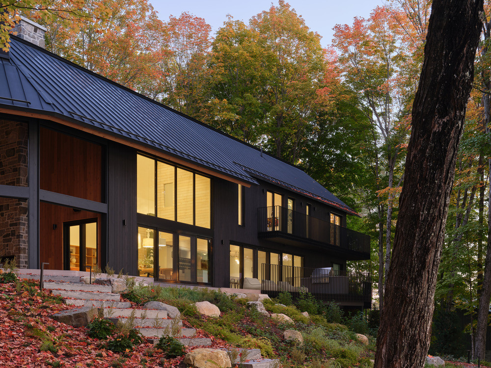 The lake-facing elevation shows the full run of lower-level glazing and the limestone stair descending through the landscape towards the water