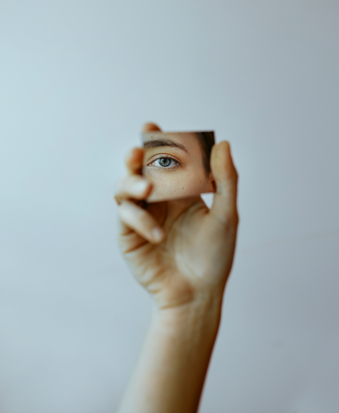 Cropped hand holding mirror with reflection of eye