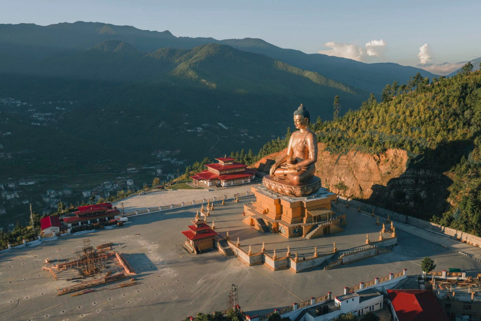 Aerial view of the golden Buddha Dordenma statue meditating peacefully against a backdrop of lush green mountains and clear skies, Thimphu, Thimphu, Bhutan.