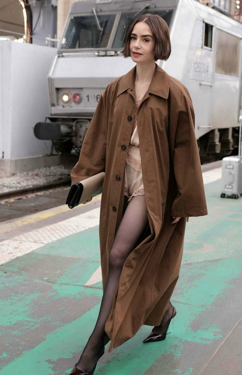 Lily Collins bước xuống tàu trong bộ jumpsuit ren và áo khoác dáng dài quá khổ ở Paris