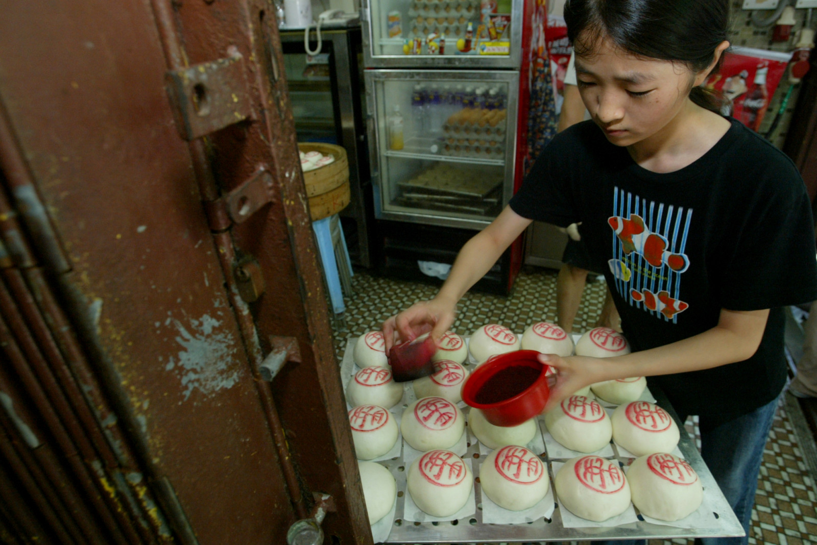 Kwok Ying, 11-year-old, puts the chop "Peace" on the Chinese steamed buns are sold at a bakery as part of the tradition in Bun Festival in Cheung Chau. 06 May 2006 (Photo by David Wong/South China Morning Post via Getty Images)