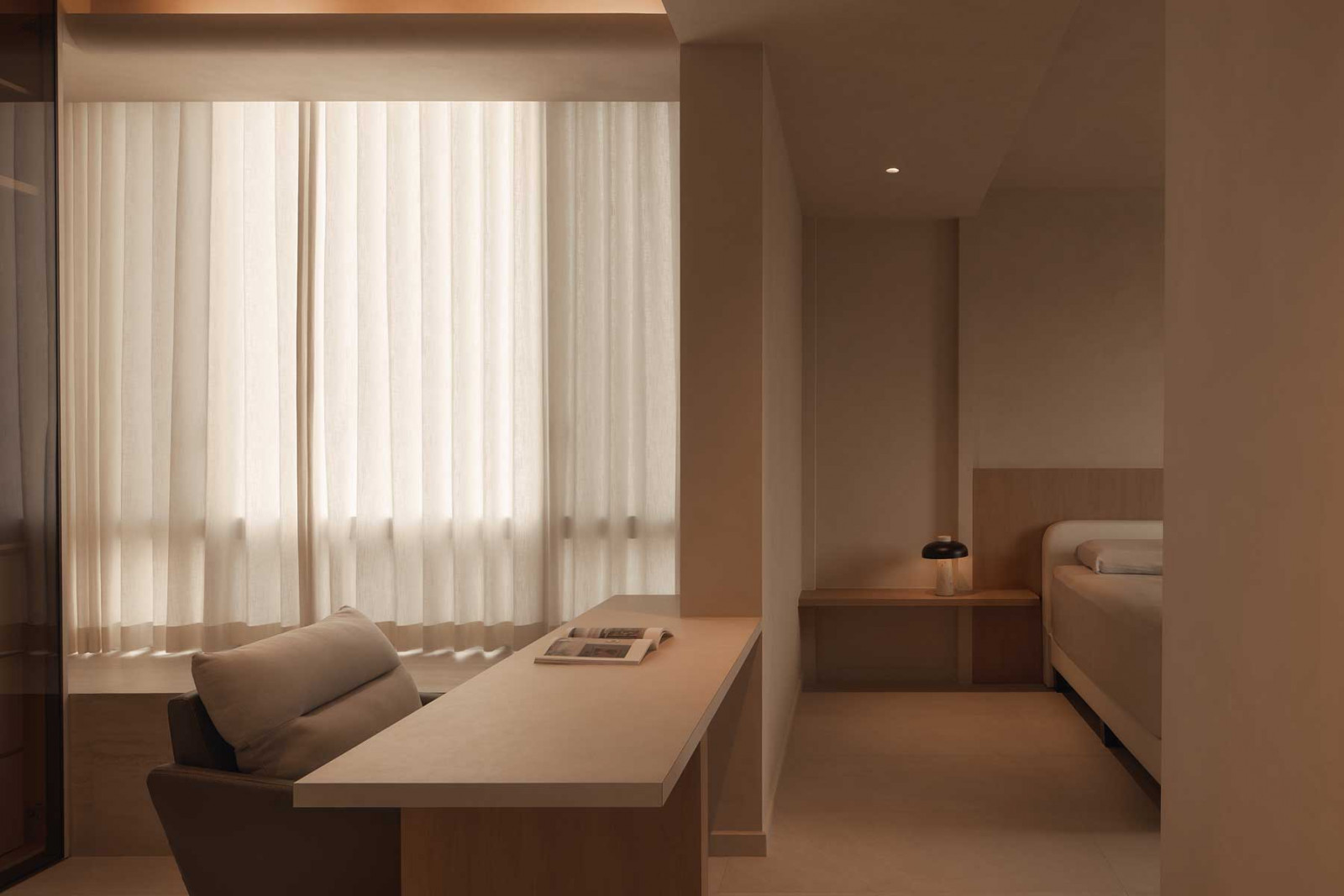 The quiet study nook is situated adjacent to the bedroom alcove, gently cocooned in warm neutrals and layered textures