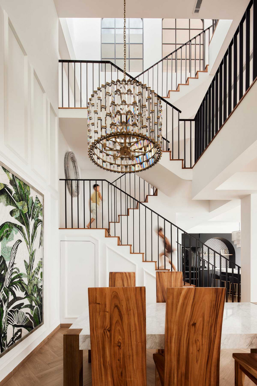 A dramatic double-volume stair hall anchors the space, crowned by a statement chandelier that emphasises the height and openness of the architecture