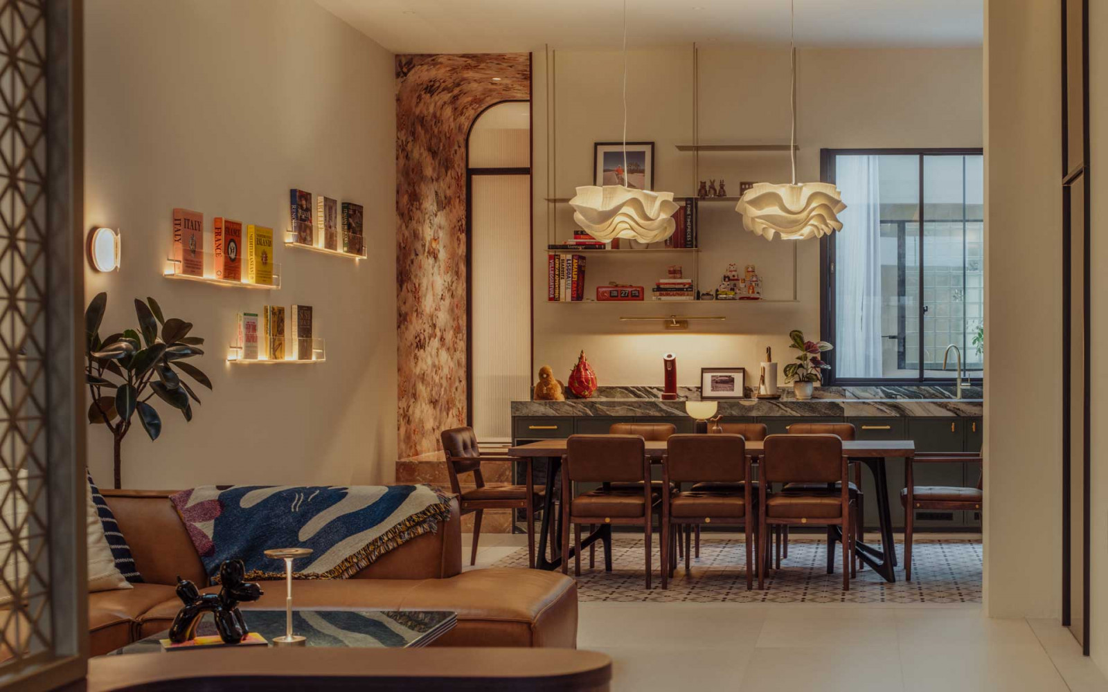 The living area flows seamlessly into the dining zone, illuminated by two zipper-inspired Kelopak pendant lamps