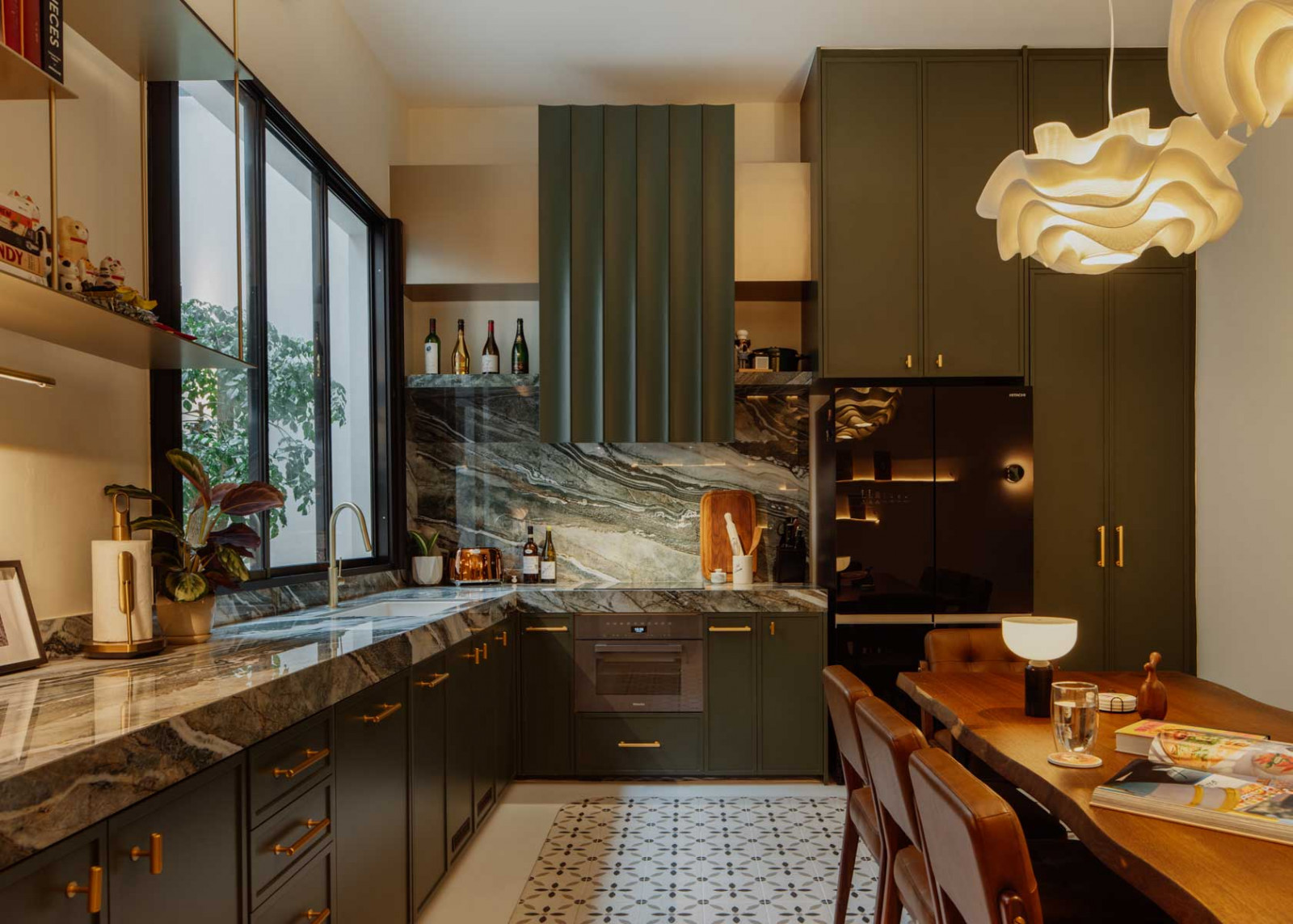 Green cabinetry with brass handles adds refined contrast, while a scallop-profiled central hood transforms a functional element into a sculptural centerpiece