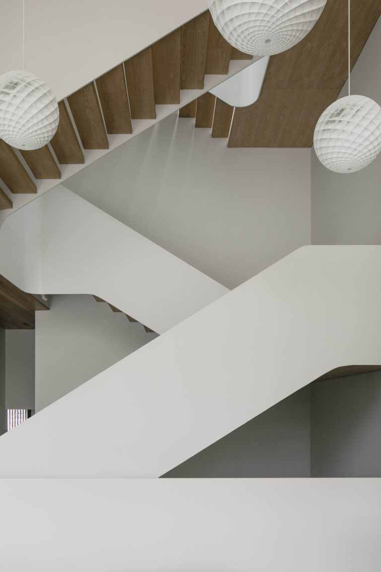 An open-riser staircase allows light to penetrate through the home