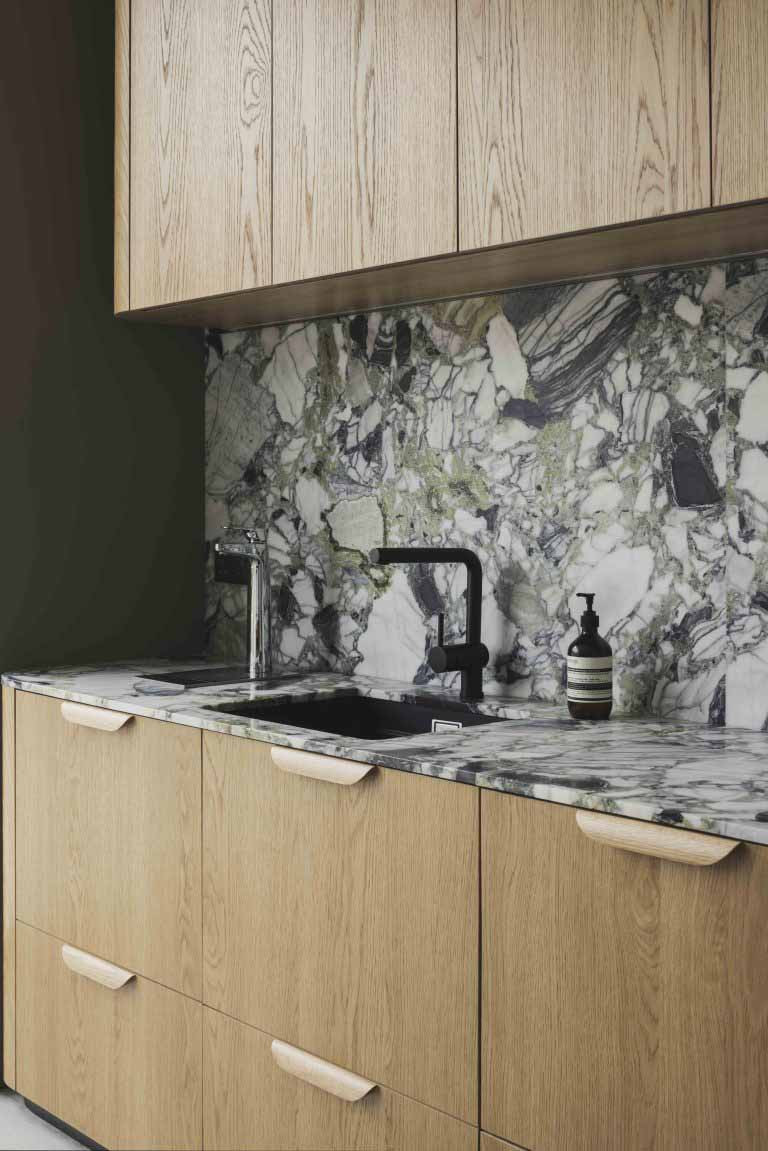 The kitchen pairs timber cabinetry with a striking marble backsplash