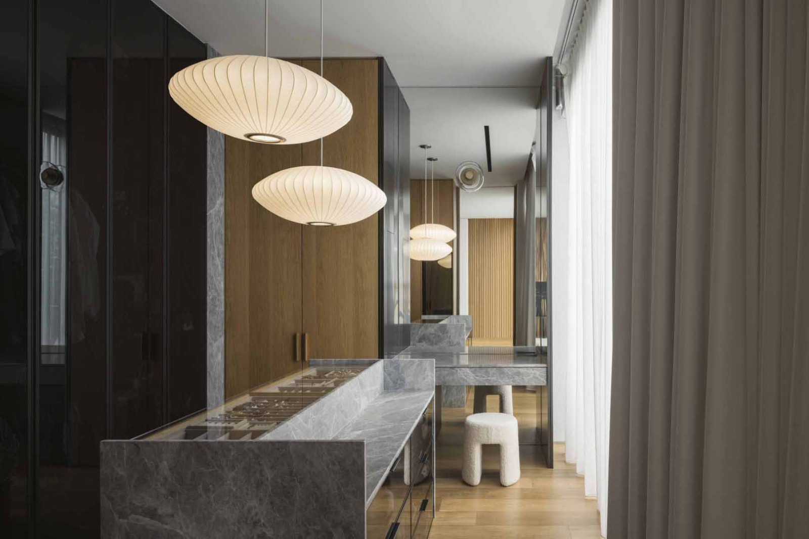 The semi-detached home’s walk-in wardrobe features stone counters and warm timber cabinetry, paired with soft pendant lighting