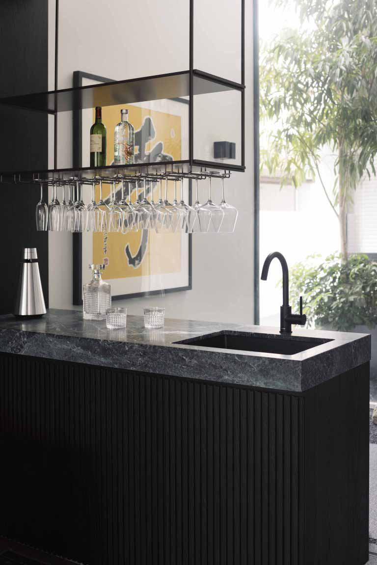 A compact bar counter integrates a sink and overhead glass rack