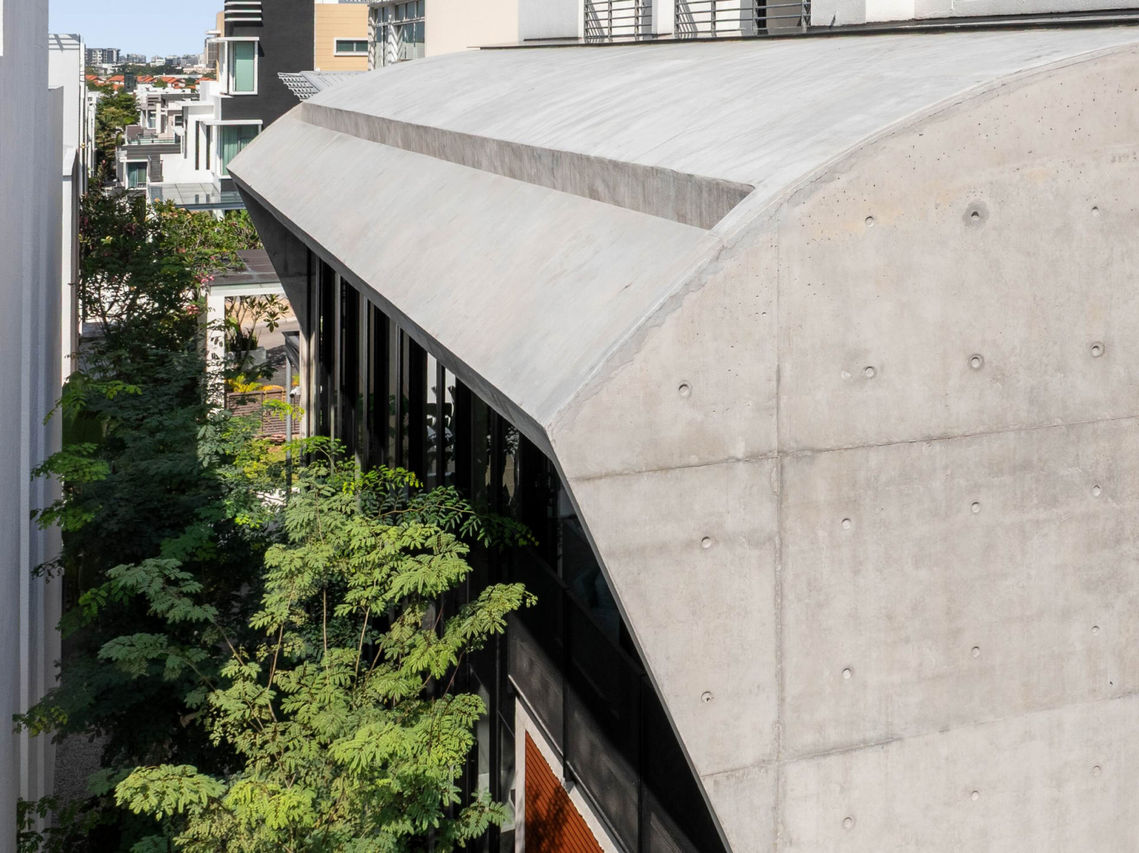 The front facade of Interface House has a curved concrete extension that rises behind the original developer bungalow, separated from it by a narrow glazed void
