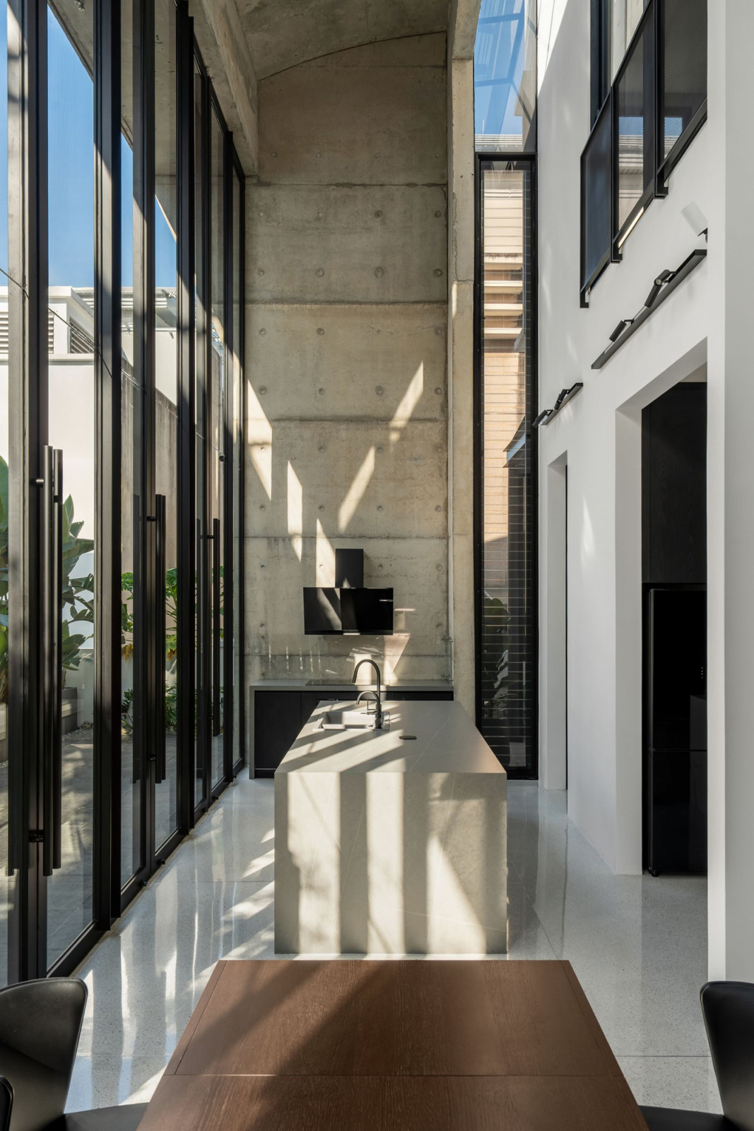 Afternoon light falls across the terrazzo floor of the hall where the kitchen island occupies the foreground
