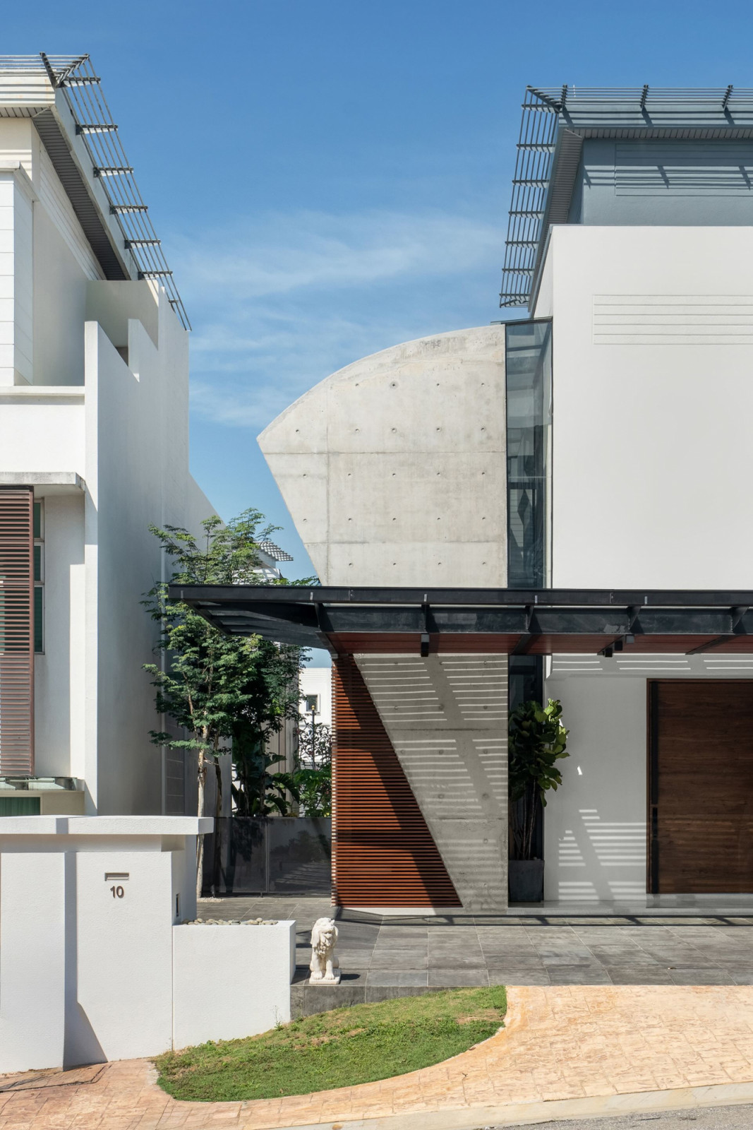 The street entrance of Interface House, with its concrete extension and curved profile and timber louvre screens, sits alongside the original two-storey bungalow