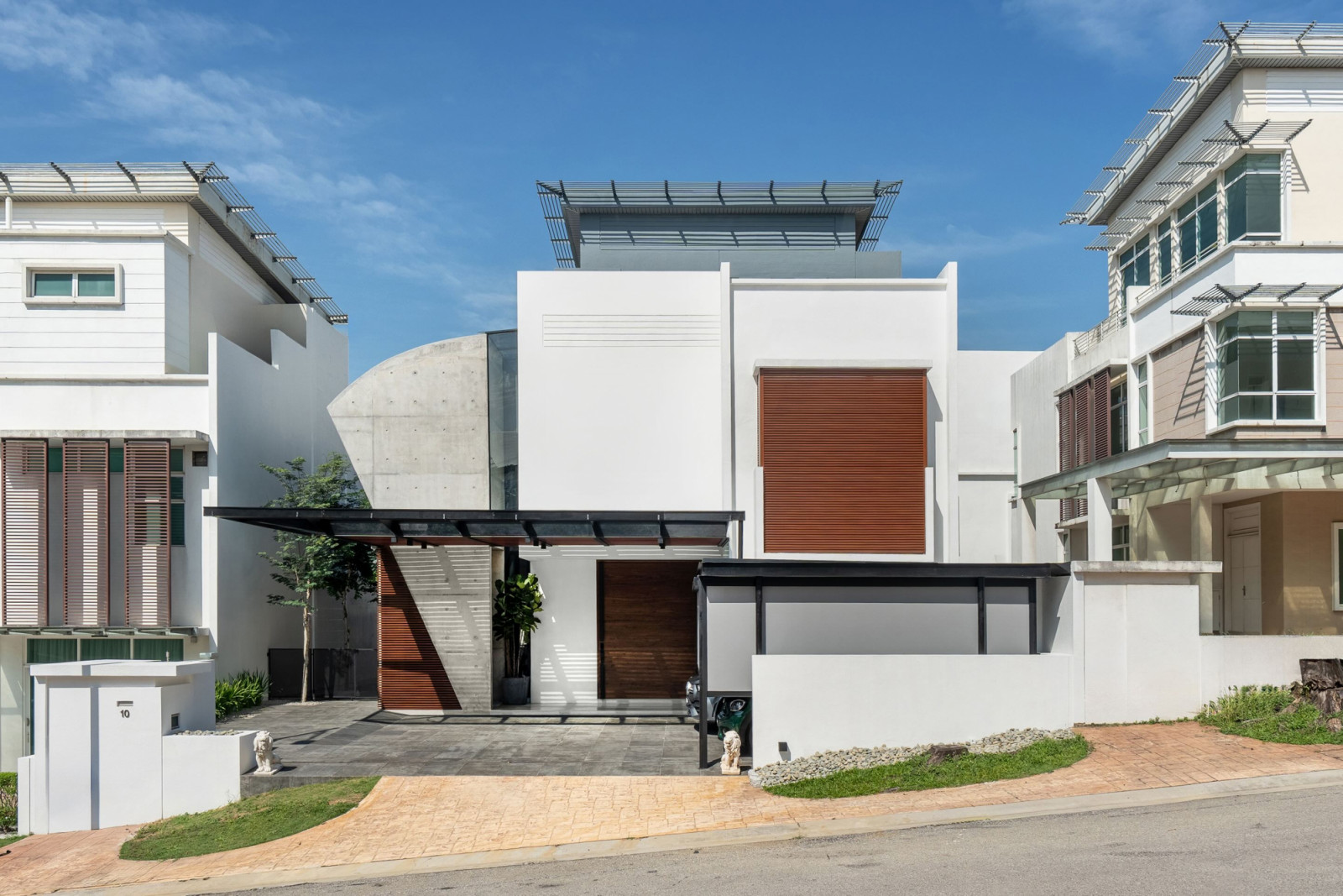 The new concrete volume reads as a distinct architectural moment set against the uniformly white-rendered forms of the surrounding development
