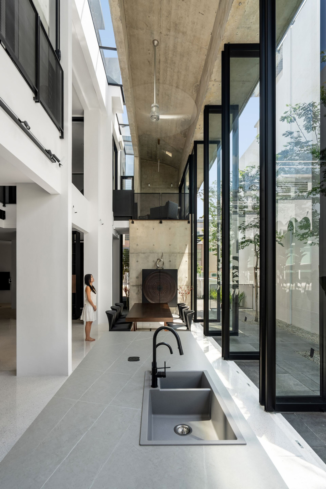 The wet kitchen counter runs along the glazed garden edge, with the dining hall and curved concrete ceiling beyond