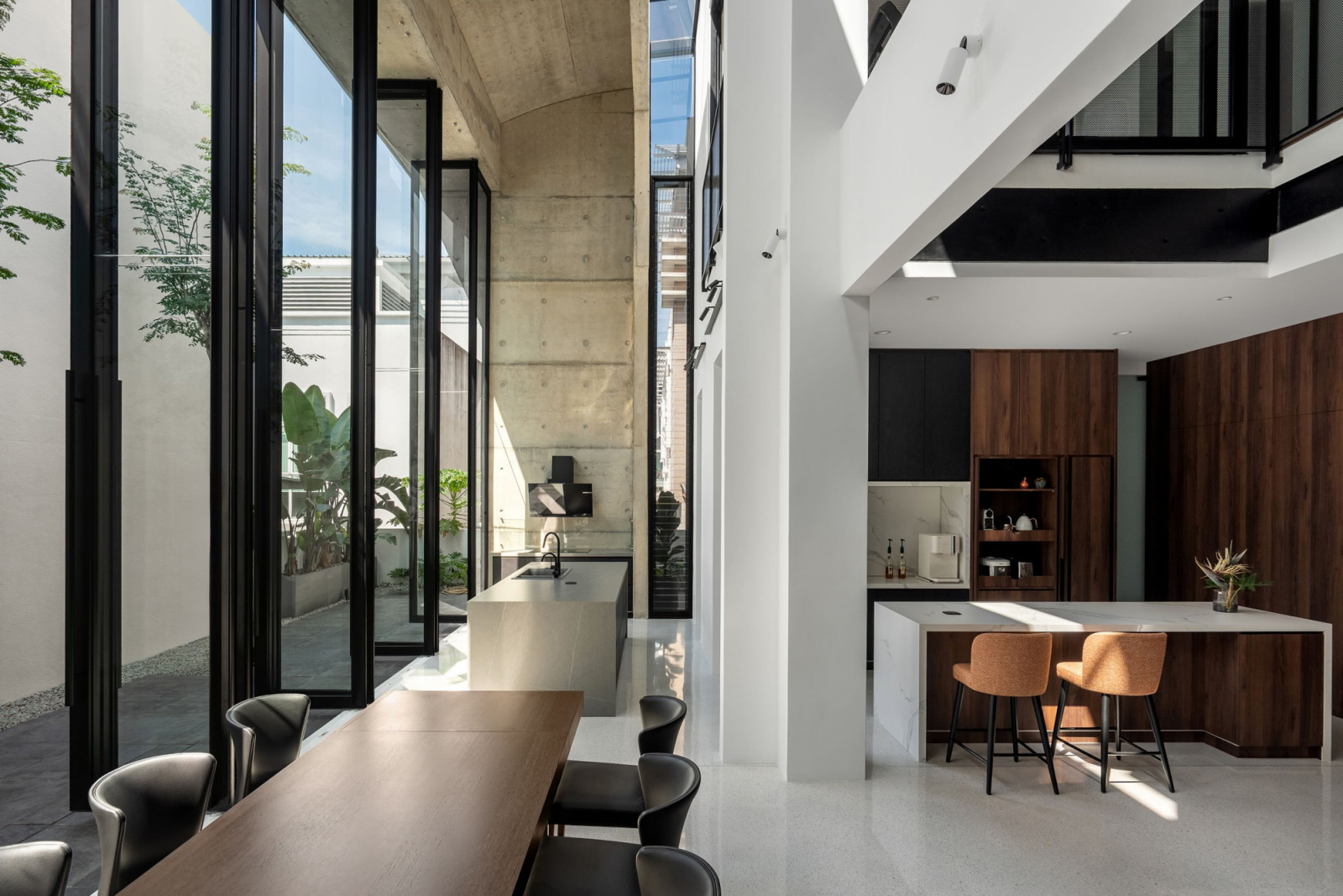 The wet kitchen island occupies the concrete extension on the left; the dry kitchen, with its timber cabinetry and marble island, sits within the original bungalow on the right
