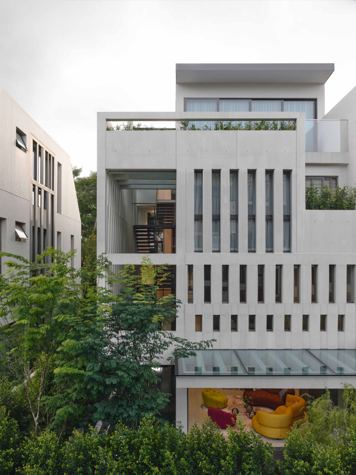 At the rear, the terrace house reveals its porosity, allowing light, air and greenery to flow through
