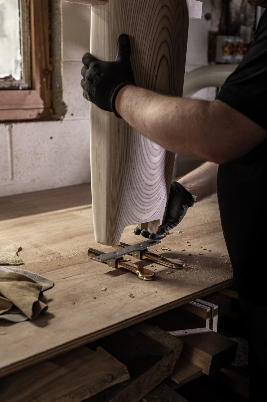A craftsperson fitting brass hardware to a birchwood leg