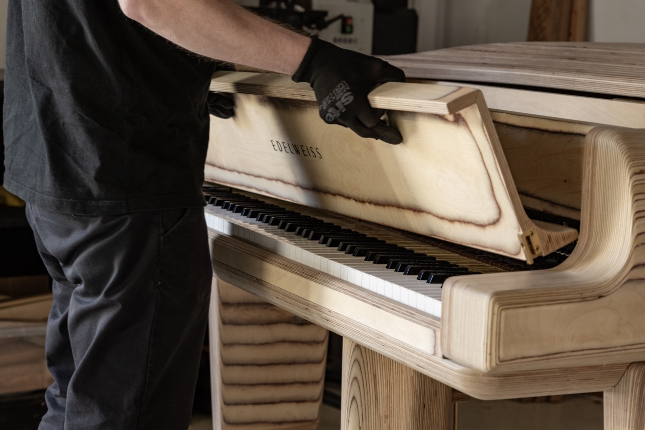 A craftsperson at the keyboard during assembly, with the Edelweiss nameplate visible beneath the key cover