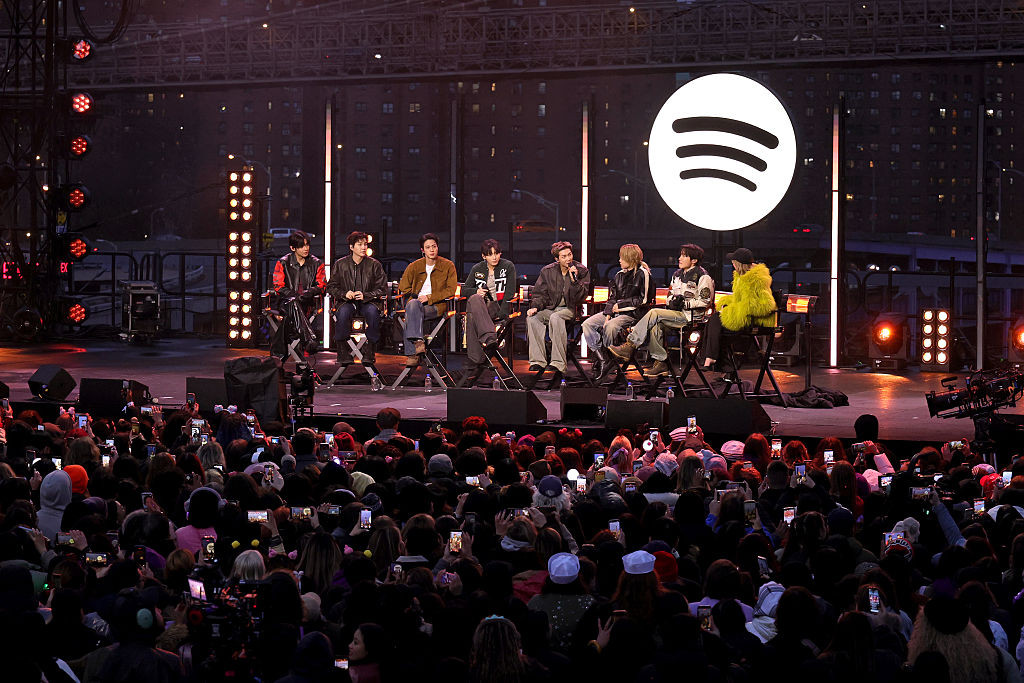 NEW YORK, NEW YORK - MARCH 23: (L-R) V, Suga, Jin, Jungkook, RM, Jimin and J-Hope of BTS and Suki Waterhouse speak onstage during Spotify x BTS: SWIMSIDE at Pier 17 on March 23, 2026 in New York City. (Photo by Kevin Mazur/Kevin Mazur/Getty Images for Spotify)