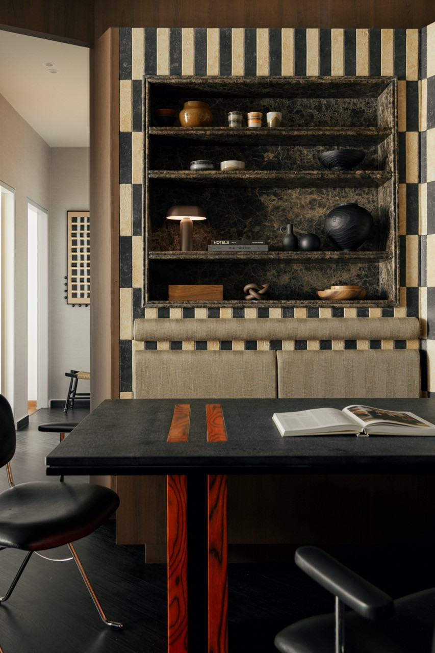 The dining table surface is in dark stone with inlaid strips of figured red-orange wood echoing the base below