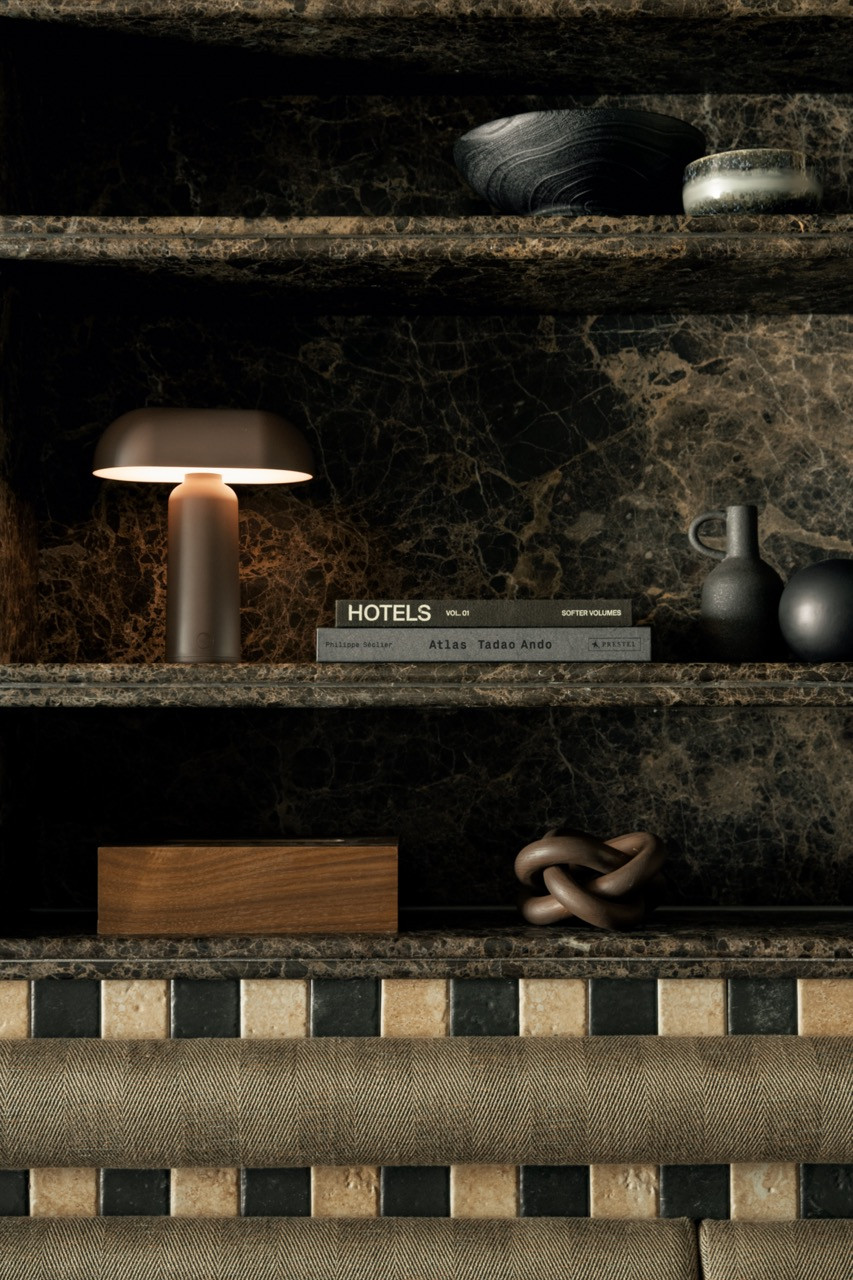 The dark marble display shelves hold ceramics, a portable table lamp, a wooden box and a Tadao Ando atlas