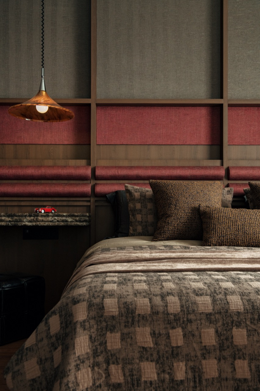 The bedroom with the copper pendant light, marble floating shelf and the layered patterned textiles on the bed
