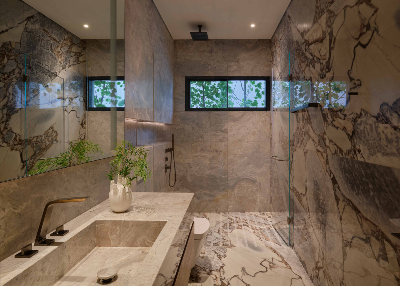 Bathroom clad in striking graphic marble, an ode to the home’s “stone plinth” base