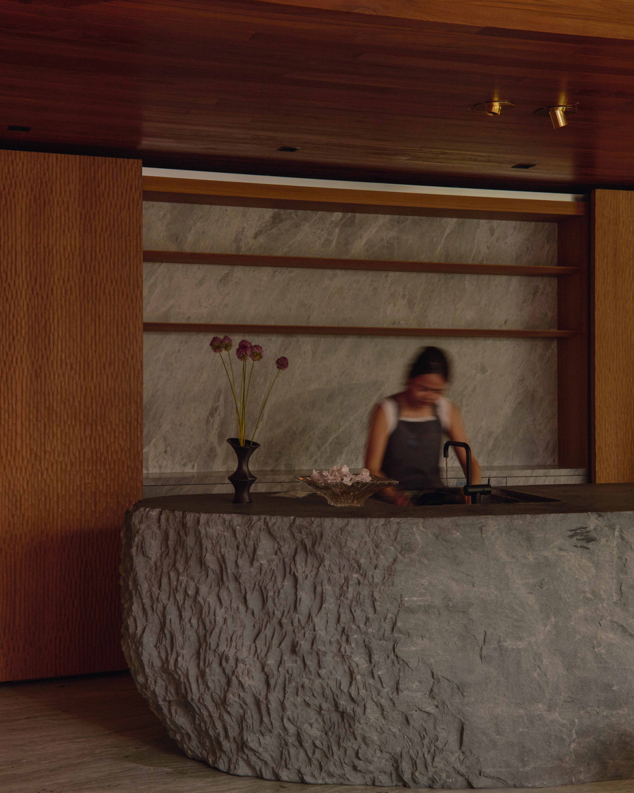A monolithic stone island is a prominent feature in this kitchen