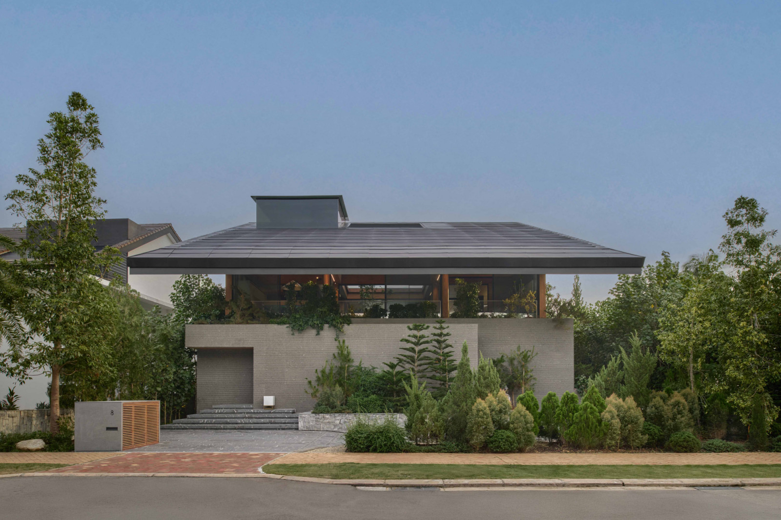 From the street, the Sentosa Cove bungalow presents its stone plinth base, shielding the private levels from passers-by