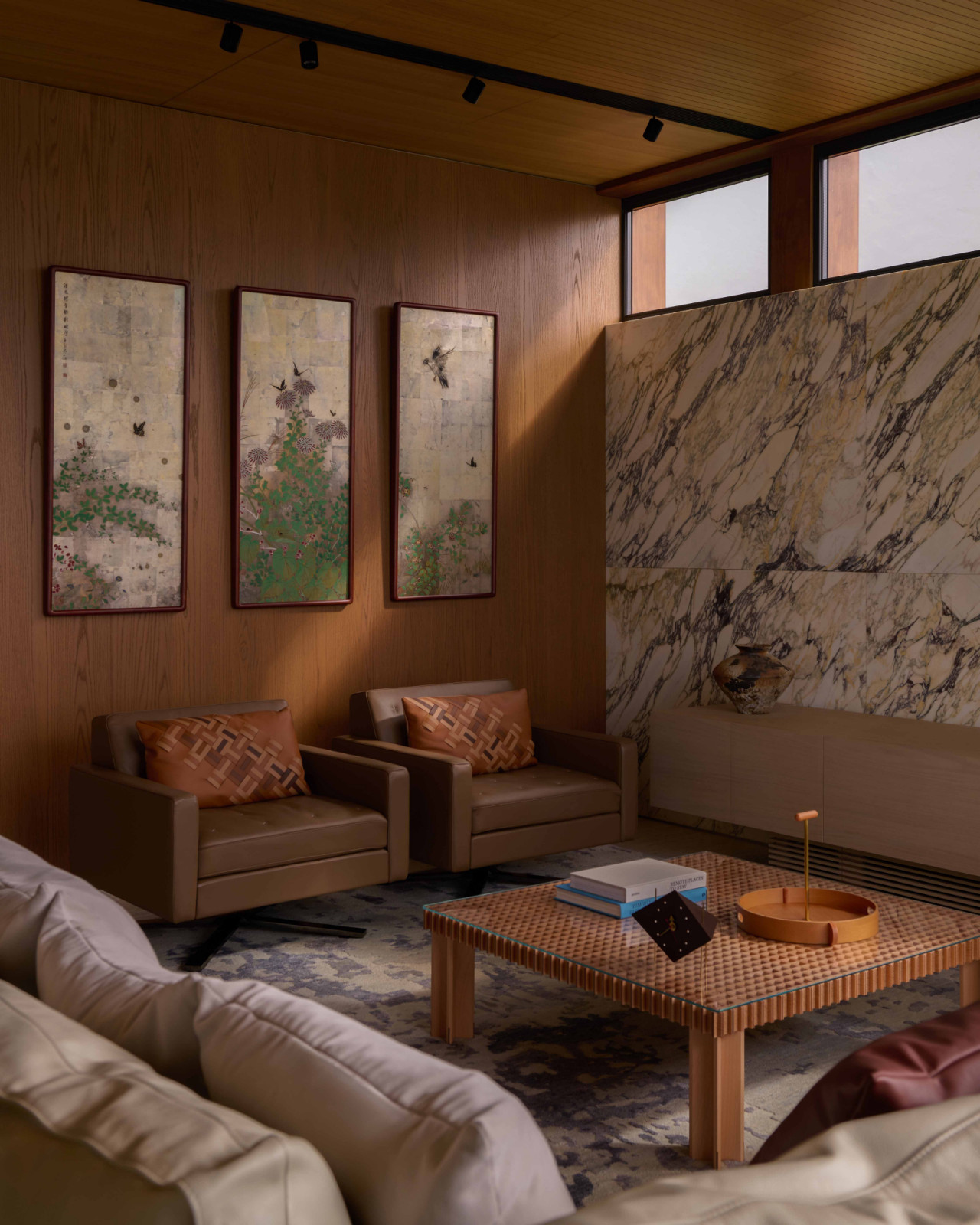 Clerestory windows cast light across the living room, where Poltrona Frau’s Kennedee armchairs and Kyoto table, supplied by Proof Living, are paired with artwork from NaWei Gallery