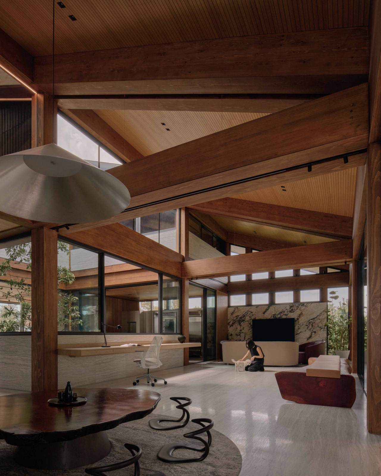 The communal level is organised on a nine-grid plan around a central courtyard, with the study and the reclaimed mahogany bench behind it flanked by seating areas