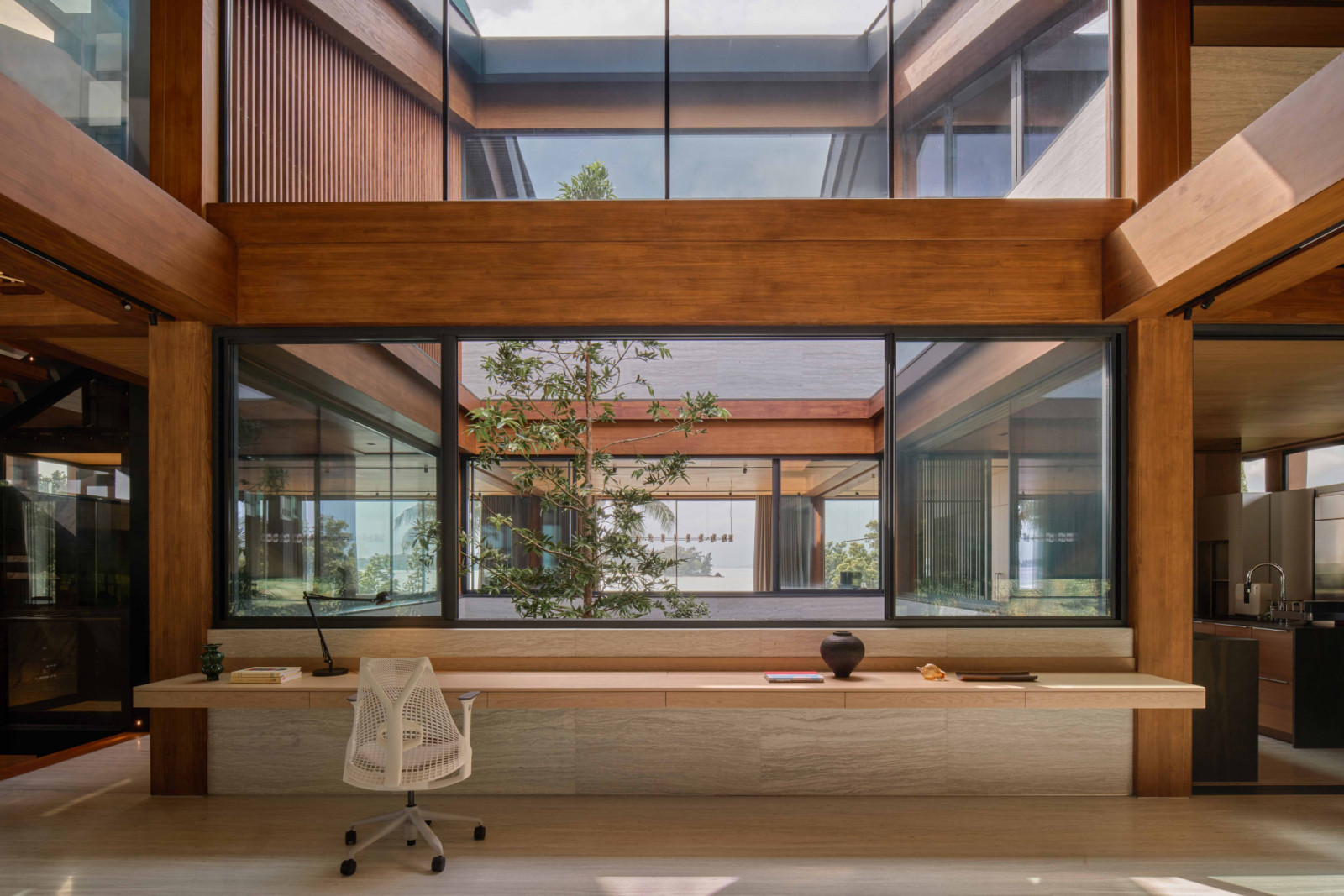 From the study area’s floating desk, views extend into the courtyard where a Borneo kauri tree rises through the house