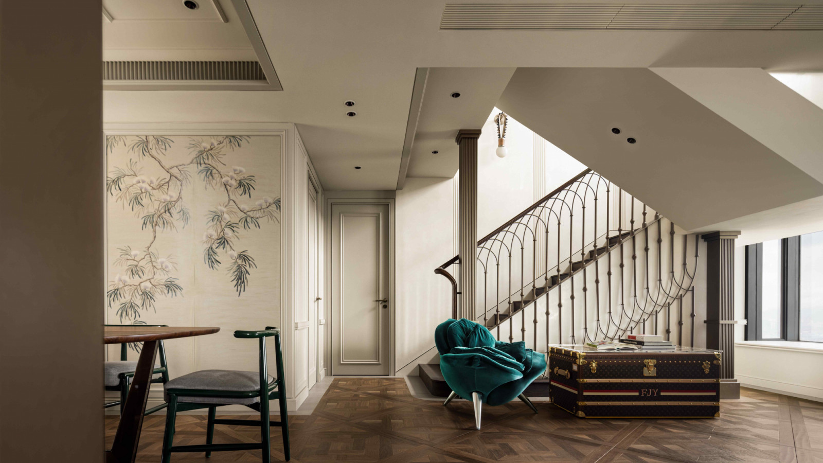 A green-accented Edra Rose Chair and a Louis Vuitton trunk chest positioned next to the staircase