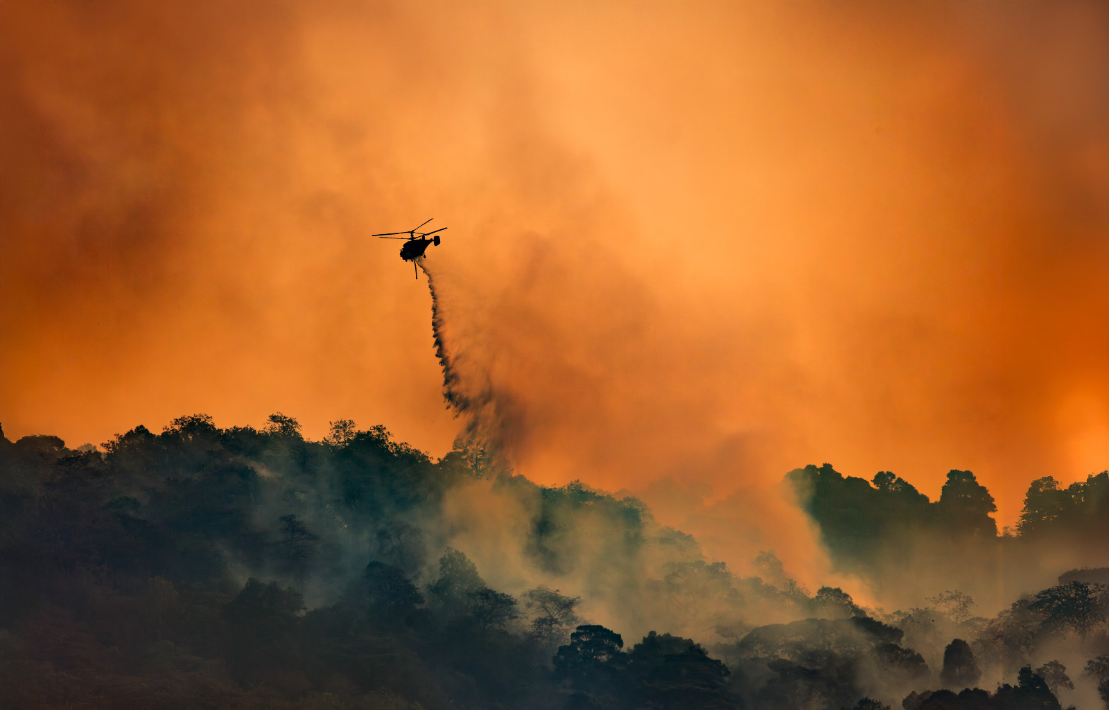Fire fighting helicopter carry water bucket to extinguish the forest fire. (photo: Toa55 / Getty Images)