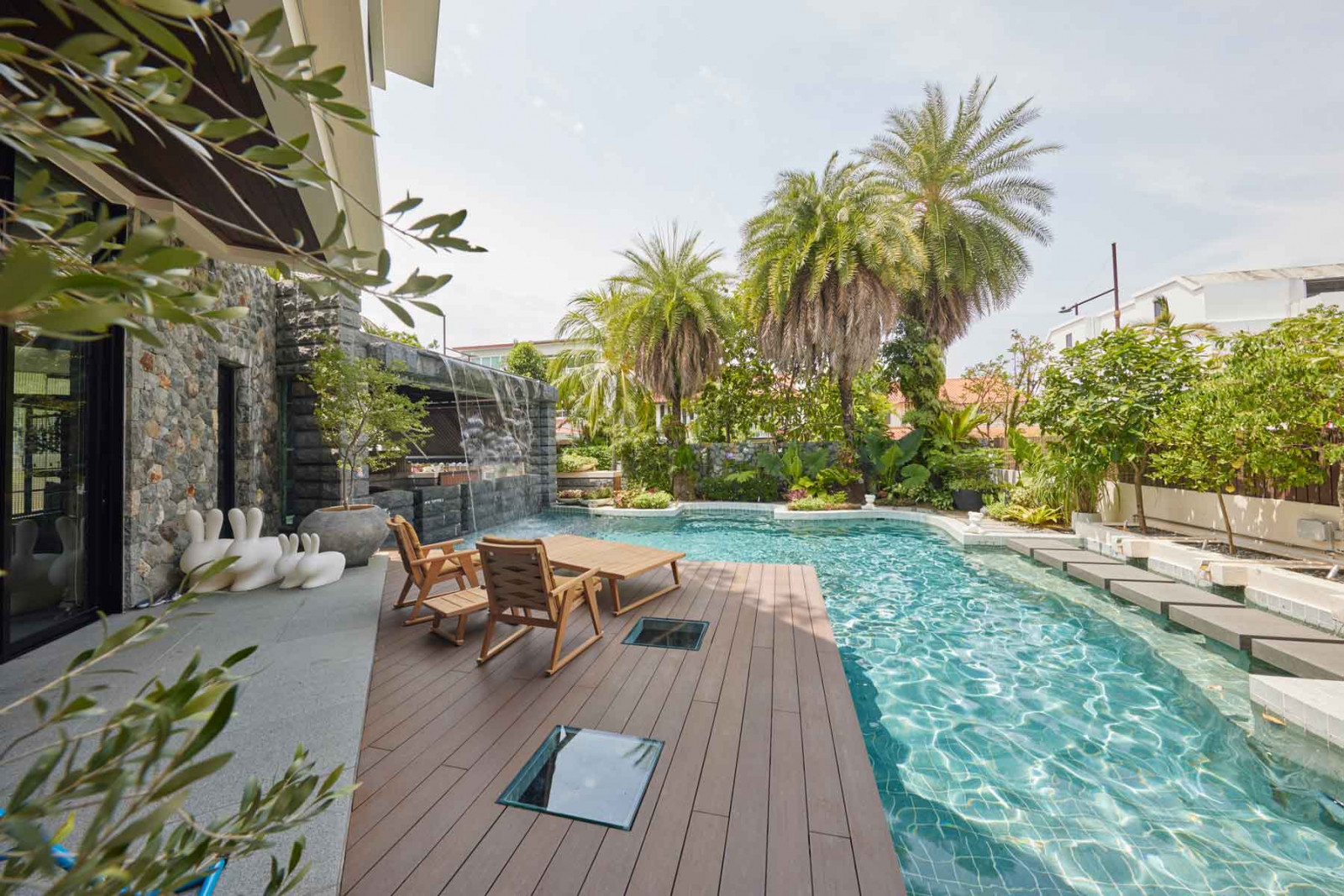 The bungalow’s lush poolscape, with a family of Qeeboo Rabbit chairs hinting at the playful nature of the interior