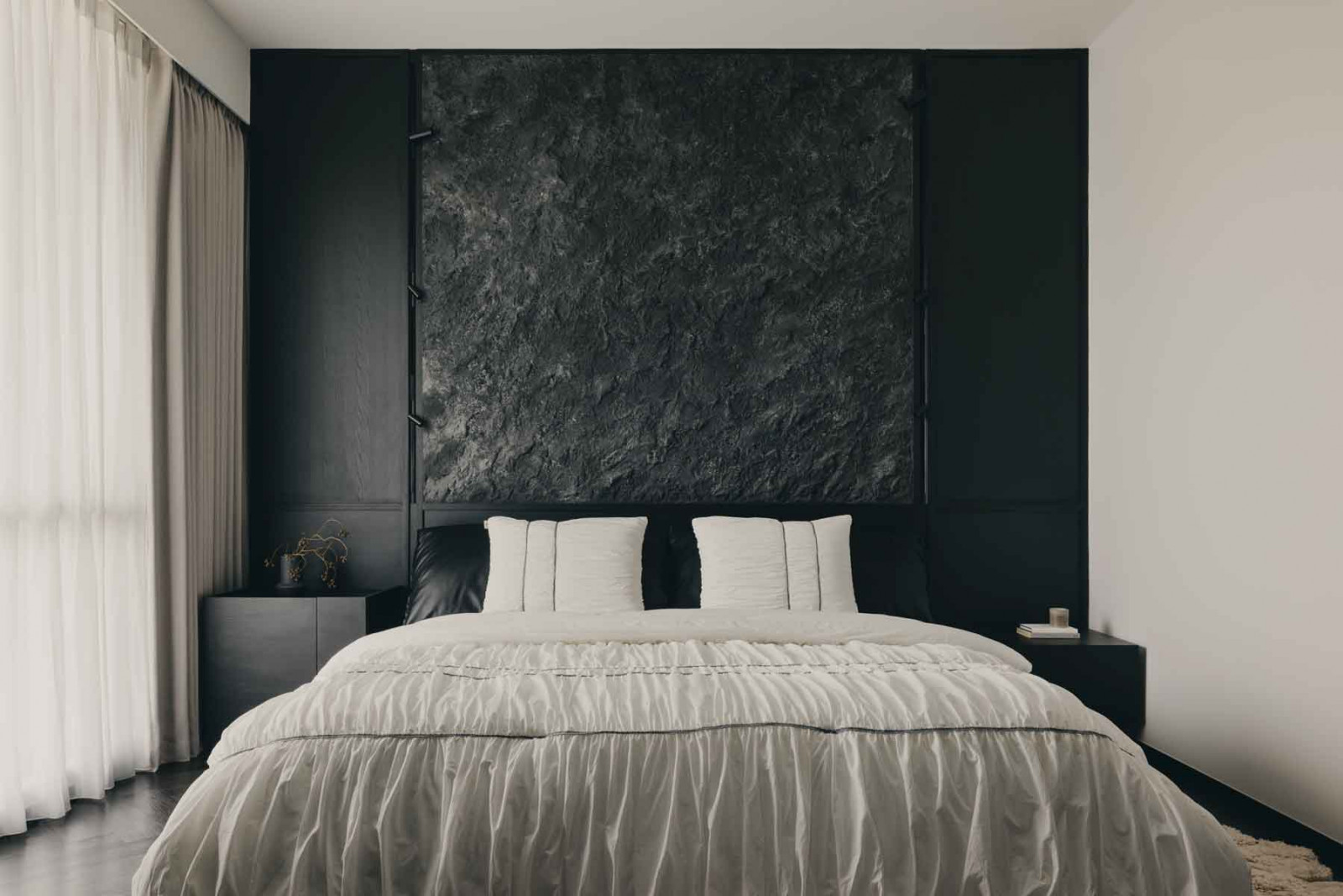 The master bedroom balances both light and dark finishes, with the textured panel above the bed acting as its focal point