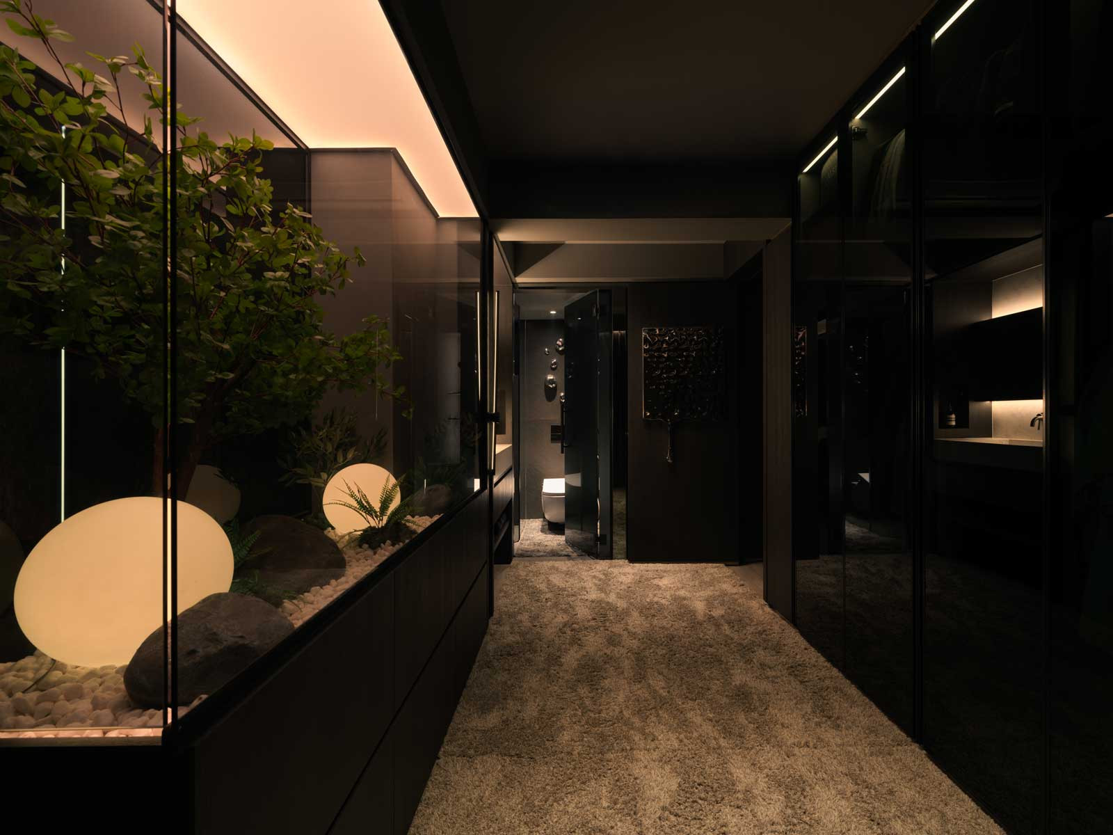 A softly carpeted corridor reveals a landscaped indoor garden framed by sleek black cabinetry, merging nature with high design